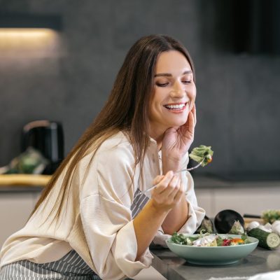 Lunch time. Smiling happy woman eating with appetite