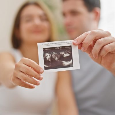 Beautiful couple holding baby ultrasound smiling at bedroom