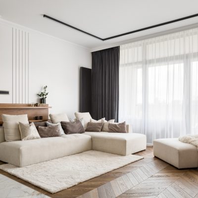Elegant and comfortable designed living room with big corner sofa, wooden floor and big windows